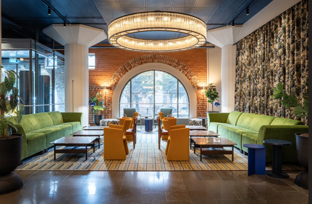 Scandic Grand Marina lobby with colourful seating, an arched window and a circular chandelier